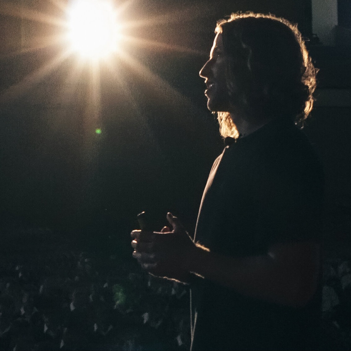 Cam Greenwood speaking on stage under a spotlight